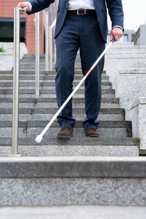 Man wearing blue suit and shoes walking down steps with a cane